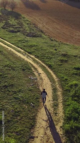 Vertical video of Drone view of  A person walks alone on a rural road