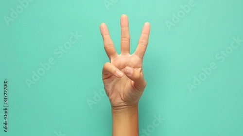 Hand Displaying Three Fingers Against a Light Green Backdrop 