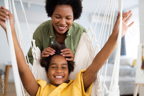 Smiling mother playing with her cute young girl in their apartment.