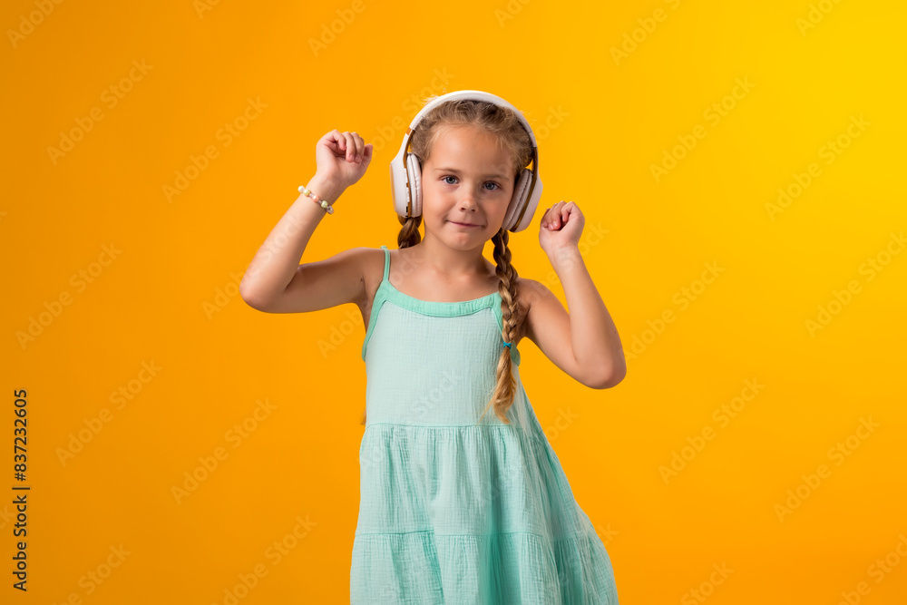 Dancing kid girl enjoying music in headphones on yellow background. Lifestyle and leasure concept Dancing kid girl enjoying music in headphones on yellow background. Lifestyle and leasure concept
