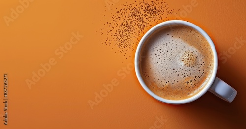 Top View of a Cup of Coffee With Cinnamon Sprinkles on an Orange Background