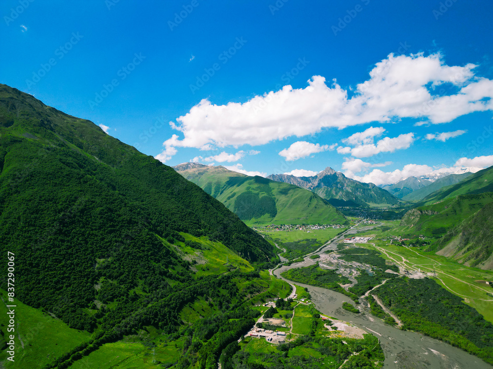 Fototapeta premium Stepantsminda tourist village of Kazbegi in the green mountains of Georgia - drone photo