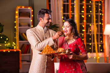 Happy young indian couple celebrate diwali festival, husband put