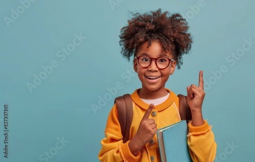 Happy Young Girl With Backpack Pointing Up Against A Blue Background