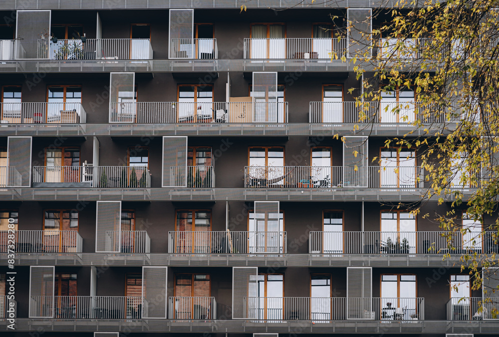 Modern European house with rows of balconies with decorative latticework and railings on summer sunny day Modern European house with rows of balconies with decorative latticework and railings on summer sunny day