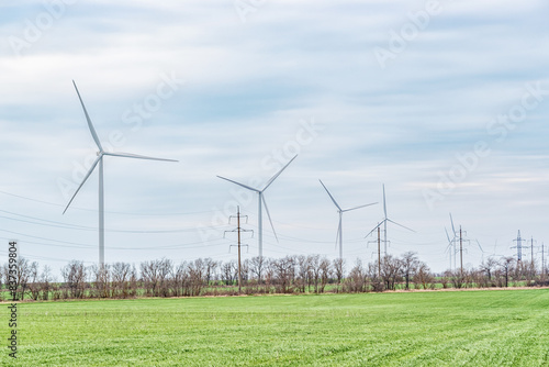 Wind turbines generating electricity in a green field. Green power generation concept.
