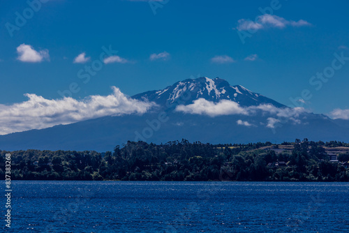 Osorno volcano mountain summit in Chile, Patagonia Andes. The ring of fire volcanic landscape with crater and lava active volcano in South America. Red rock frozen lava and snow on volcano top