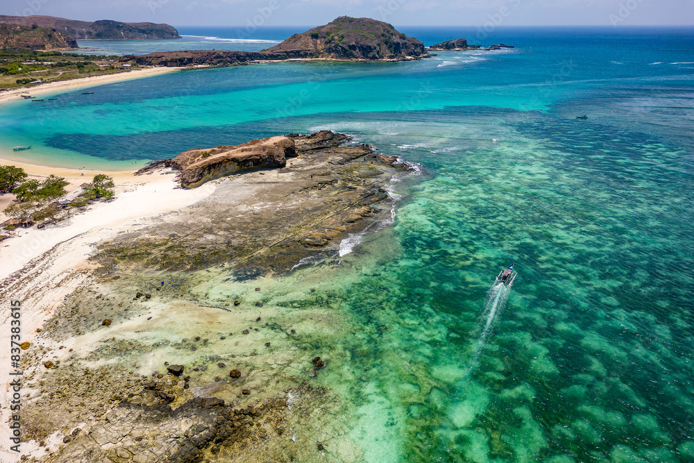 Fototapeta premium Aerial view of traditional boats moored in a warm, shallow ocean off a tropical beach (Tanjung Aan, Lombok, Indonesia)