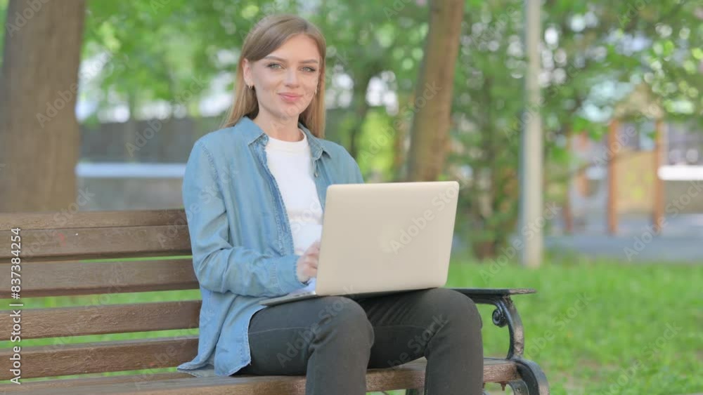 Thumbs Up by Young Woman Using Laptop while Sitting Outdoor on Bench Thumbs Up by Young Woman Using Laptop while Sitting Outdoor on Bench