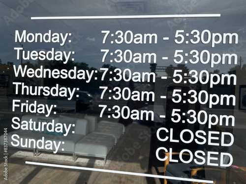 Store hours sign on a glass door closed Saturday and Sunday