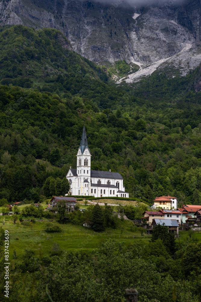 Fototapeta premium San Fermin Church immersed in the green of the Slovenian mountains a few steps from Caporetto. It remains a precious gem of Christianity and faith to be admired, makes the view of the mountain unique.