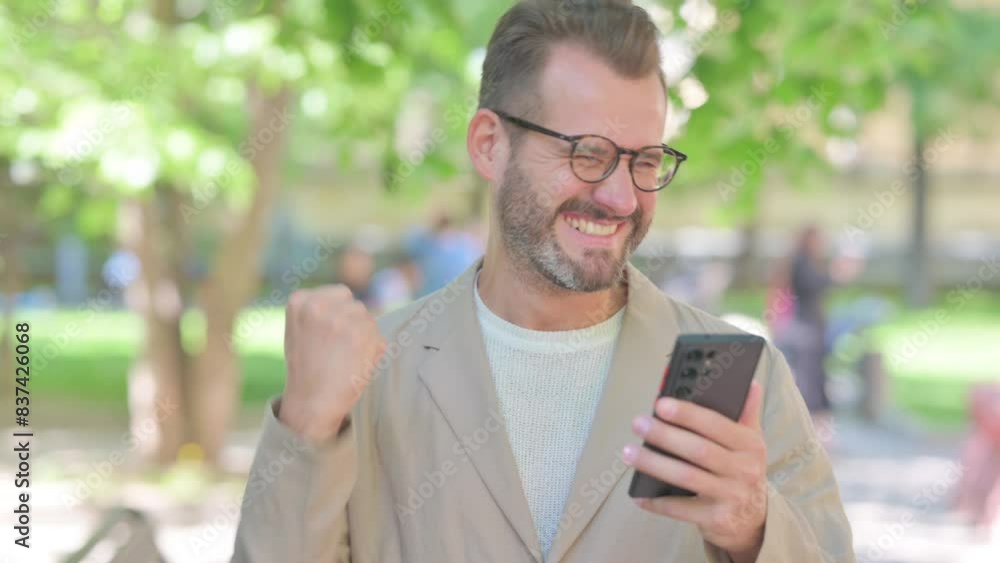 Businessman Celebrating Trade on Phone Outdoor in Park Businessman Celebrating Trade on Phone Outdoor in Park