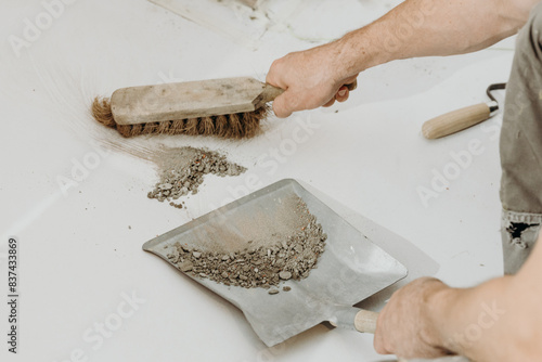 A builder man sweeps up construction debris with a broom.