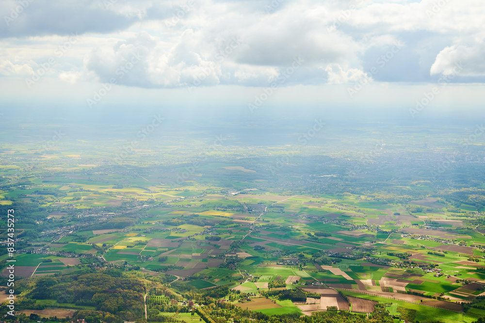 Flying over European country. Aerial view of European countryside and agricultural lands from an airplane window. Flying over European country. Aerial view of European countryside and agricultural lands from an airplane window.