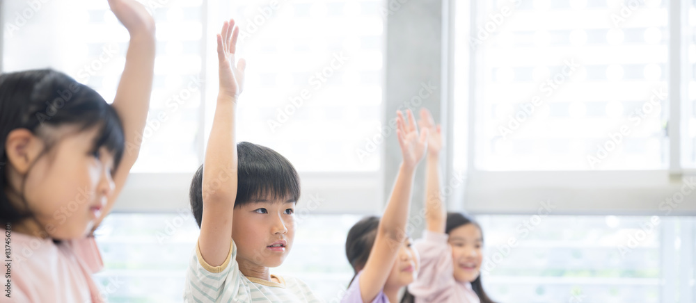 Fototapeta premium 授業を受ける小学生 ハイと手を挙げ挙手をするバナー