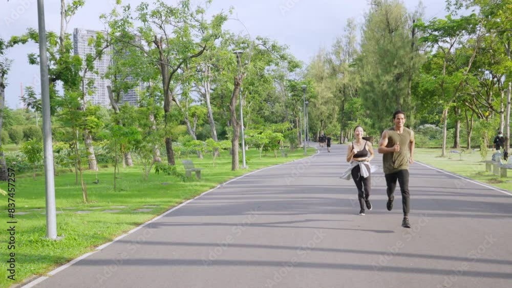 Asian couple in sportswear jogging exercise at public park together in summer morning. Healthy man and woman athlete enjoy outdoor activity lifestyle sport training fitness running workout in the city Asian couple in sportswear jogging exercise at public park together in summer morning. Healthy man and woman athlete enjoy outdoor activity lifestyle sport training fitness running workout in the city