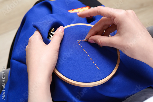 Vászonkép Woman with sewing needle and thread embroidering on cloth, closeup