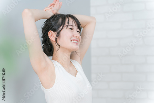 家でストレッチ・柔軟体操をするアジア人女性（脱毛・ヨガ）
