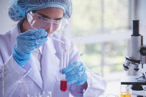 Scientist woman holding chemical test glass tube testing science laboratory. Lab technician holding red drop to glass tube diagnosis blood sample. Asian woman scientist working test medical chemistry