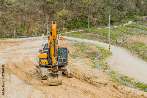 Fotografi Front view of backhoe parked at rural construction site.