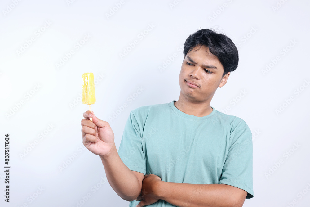 Potrait Of Confused Young Asian Man Holding While Looking Ice Cream Isolated On White Background Potrait Of Confused Young Asian Man Holding While Looking Ice Cream Isolated On White Background