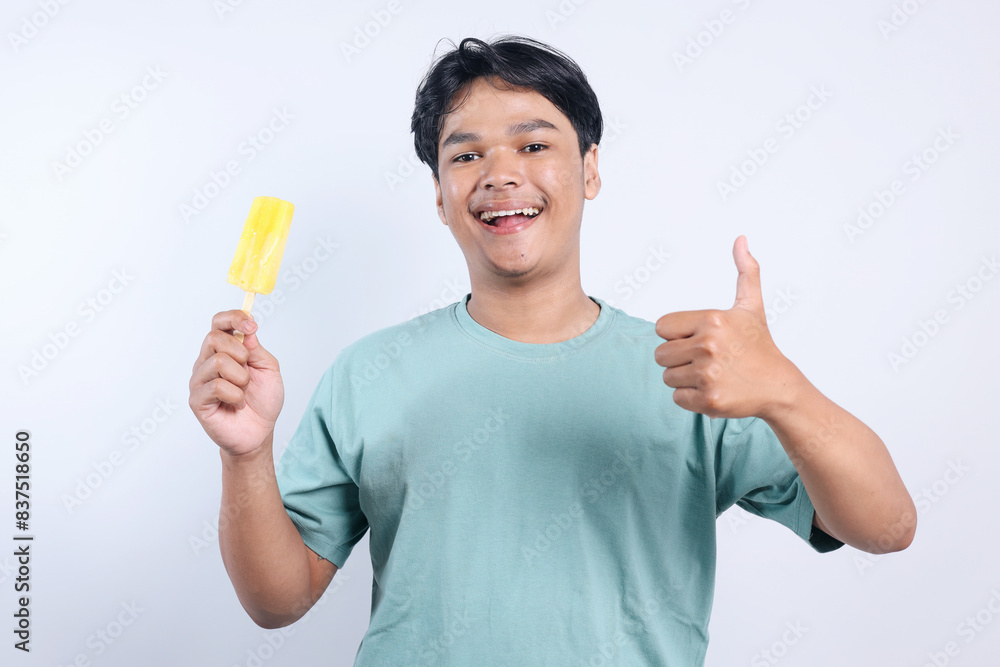 Potrait Of Cheerful Young Asian Man Holding Ice Cream And Givibg Thumbs Up Isolated On White Background Potrait Of Cheerful Young Asian Man Holding Ice Cream And Givibg Thumbs Up Isolated On White Background