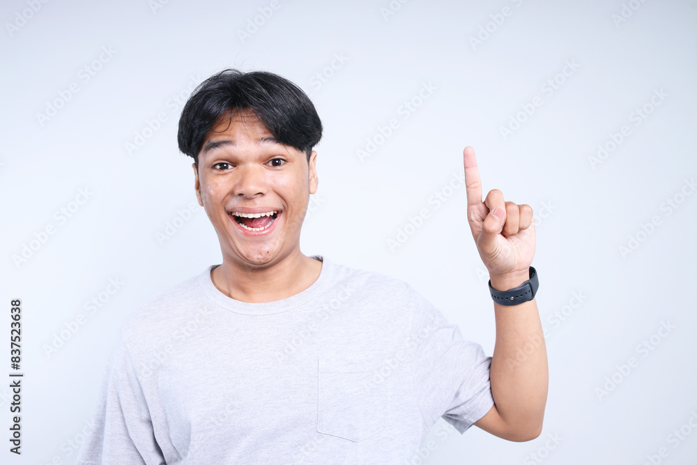Potrait Of Cheerful Young Asian Man Pointing To Upwards For Free Space Isolated On White Background Potrait Of Cheerful Young Asian Man Pointing To Upwards For Free Space Isolated On White Background
