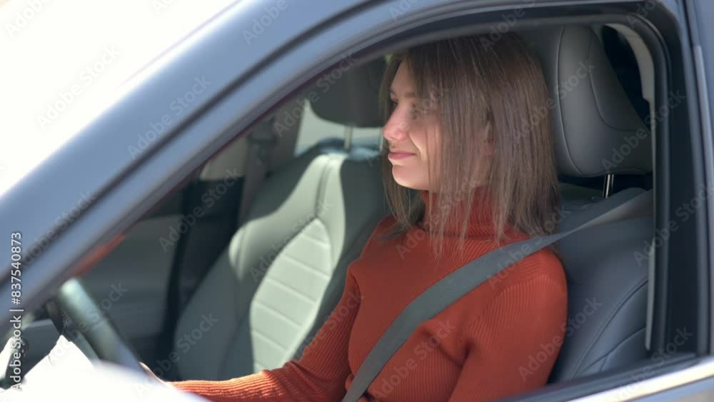 A young woman with brown hair in an orange sweater beeps her car horn, displaying a frustrated expression while driving A young woman with brown hair in an orange sweater beeps her car horn, displaying a frustrated expression while driving