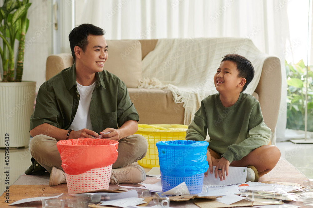 Cheerful father and son learning sorting waste