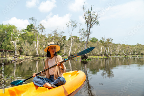 Holiday travel activities. Happy asian woman rowing a canoe or kayak in mangrove forests. Young traveler with kayak at botanical garden tropical mangrove forest in a national park.