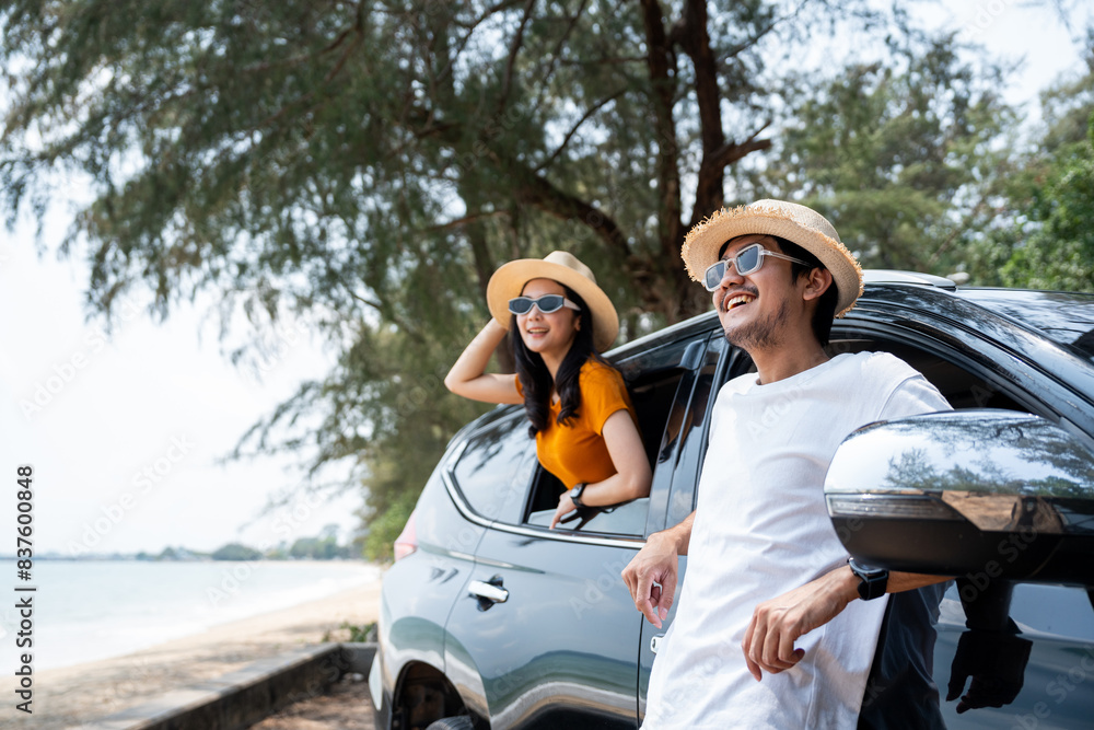 Young asian couple man and woman travel by car on a bright day to the sea sand beach with beautiful blue sky sunlight. They was happy along the way trip. safety driving car vacation. Young asian couple man and woman travel by car on a bright day to the sea sand beach with beautiful blue sky sunlight. They was happy along the way trip. safety driving car vacation.
