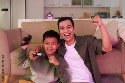Joyful father and son celebrating winning videogame