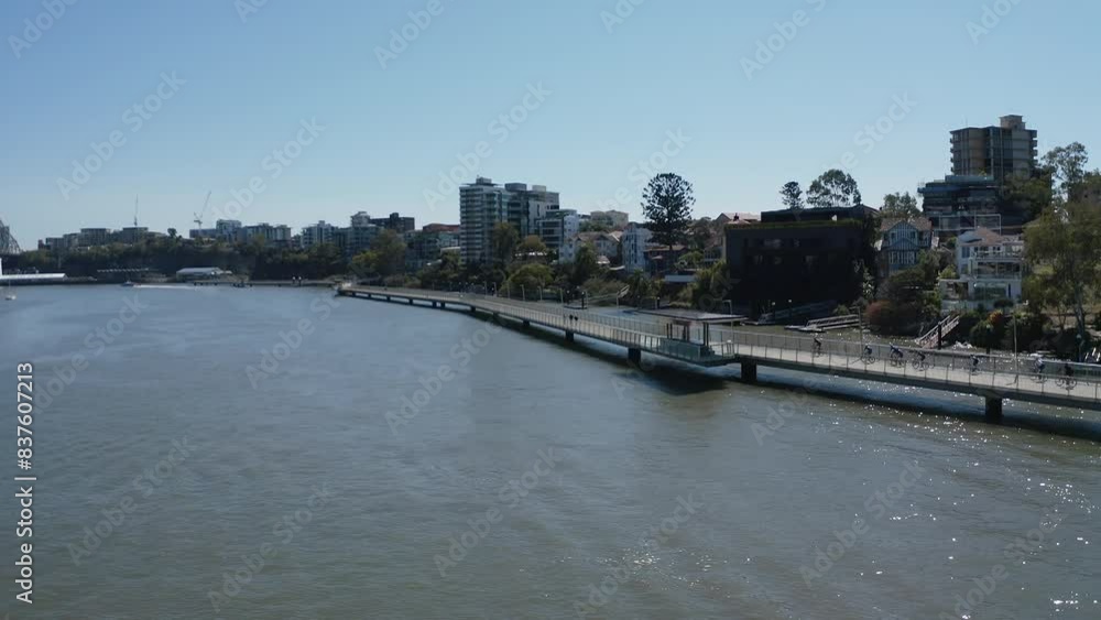 Drone wide shot flying along Brisbane river in New Farm, following a group of cyclist as they ride along the new farm river walk. Tracking pushing forward shot. Drone wide shot flying along Brisbane river in New Farm, following a group of cyclist as they ride along the new farm river walk. Tracking pushing forward shot.