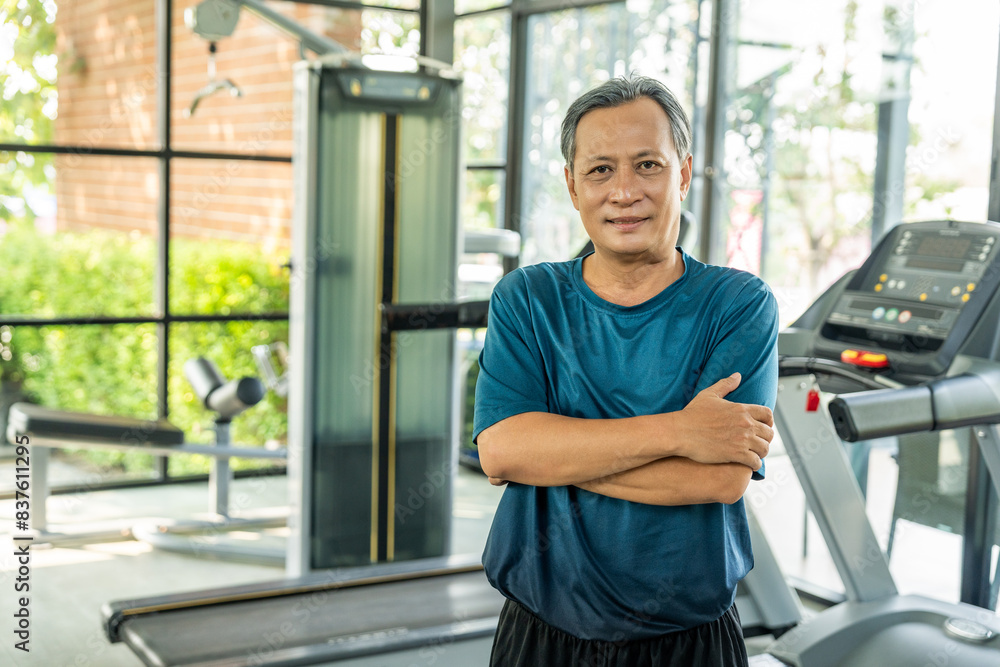 Senior asian man wearing sportswear warming up in fitness gym before exercise. Mature man stretching arm before running. Training athlete work out Senior asian man wearing sportswear warming up in fitness gym before exercise. Mature man stretching arm before running. Training athlete work out
