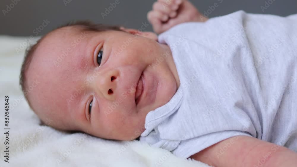 Infancy, healthcare and pediatrics, growth. Close up view of cutie newborn wearing bodysuit lying alone on bed adorable baby resting on bedsheets moving playing Infancy, healthcare and pediatrics, growth. Close up view of cutie newborn wearing bodysuit lying alone on bed adorable baby resting on bedsheets moving playing