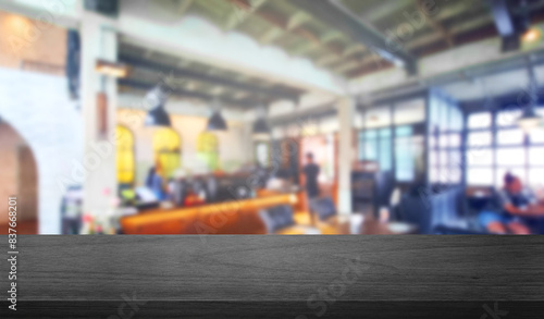 dark black wooden table at foreground with blurred view of modern industrial cafe restaurant used as product displayed. modern cafe interior with metallic frame, wooden floor and ceiling.