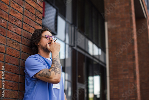 Healthcare worker taking a break  smoking a cigarette outdoors  in front of the hospital building.