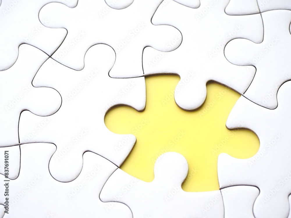 A close-up of an incomplete jigsaw puzzle with one missing piece on a yellow background, symbolizing incompleteness, imperfection, mistery or loss A close-up of an incomplete jigsaw puzzle with one missing piece on a yellow background, symbolizing incompleteness, imperfection, mistery or loss