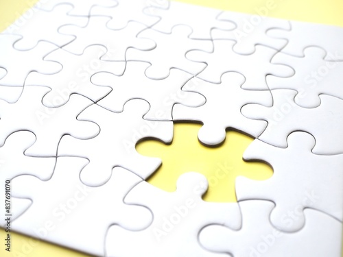 Incomplete jigsaw puzzle with one missing piece on a yellow background, symbolizing incompleteness, imperfection, mistery or loss