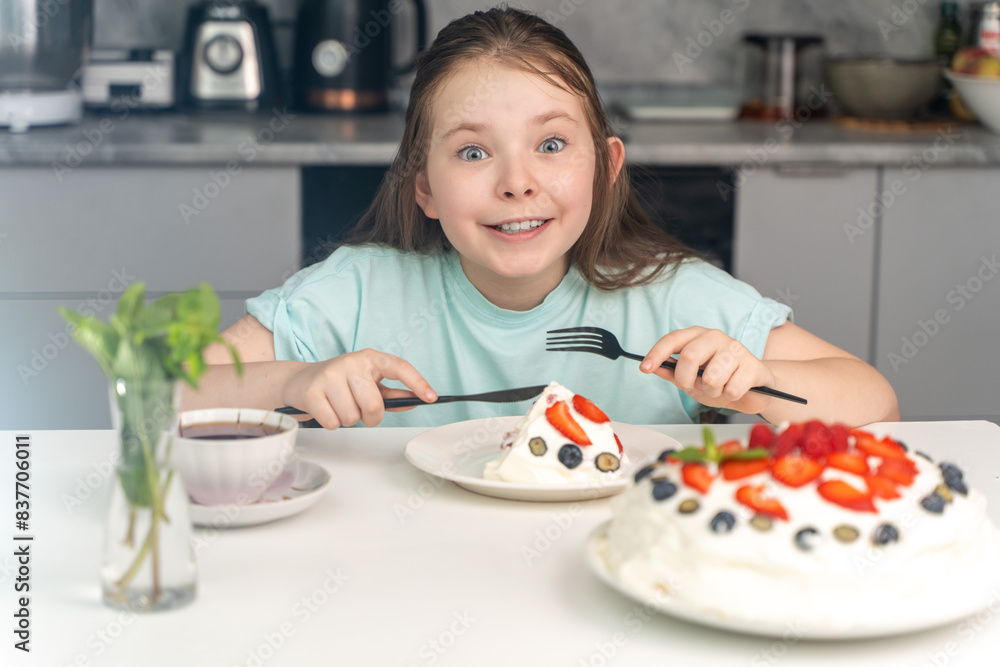 Happy little girl eating cake while sitting at table in kitchen at home. Selected focus. Happy little girl eating cake while sitting at table in kitchen at home. Selected focus.