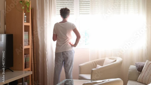 Serene Dawn: After awakening, a person calmly and expectantly walks to the window, pulls aside the curtain to see the soft light of the morning and the beauty of the new day