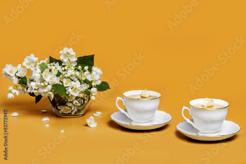 Jasmine tea with fresh flowers isolated on orange background
