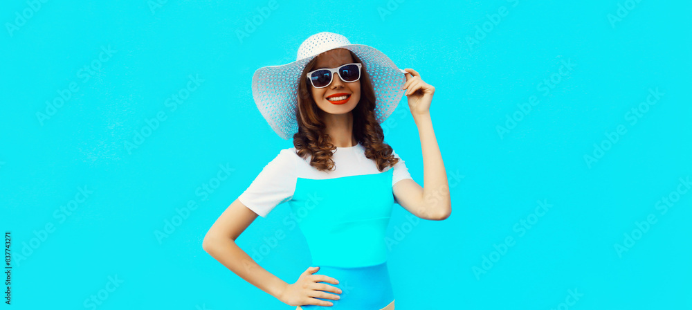 Beautiful young woman posing wearing summer straw hat, dress on blue background Beautiful young woman posing wearing summer straw hat, dress on blue background