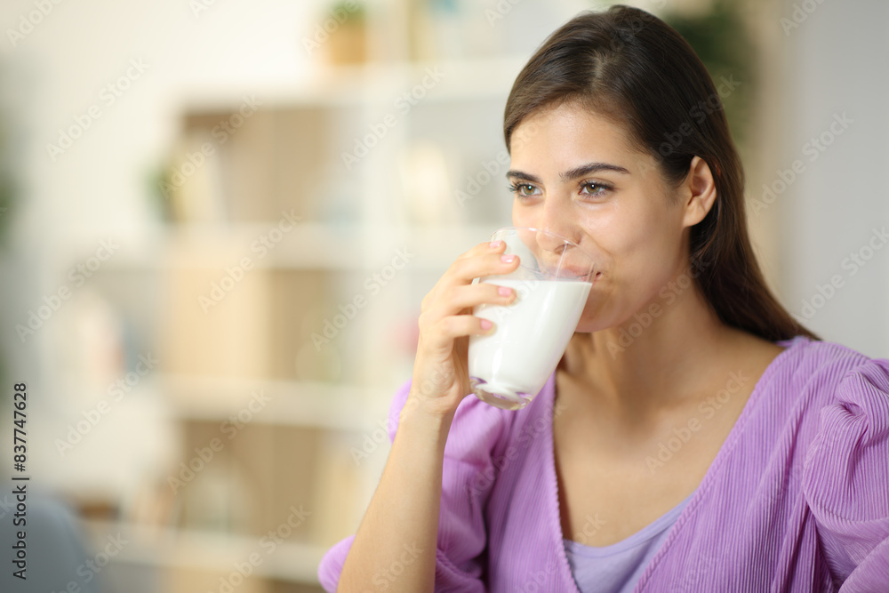 Happy woman drinking milk from glass looking away Happy woman drinking milk from glass looking away