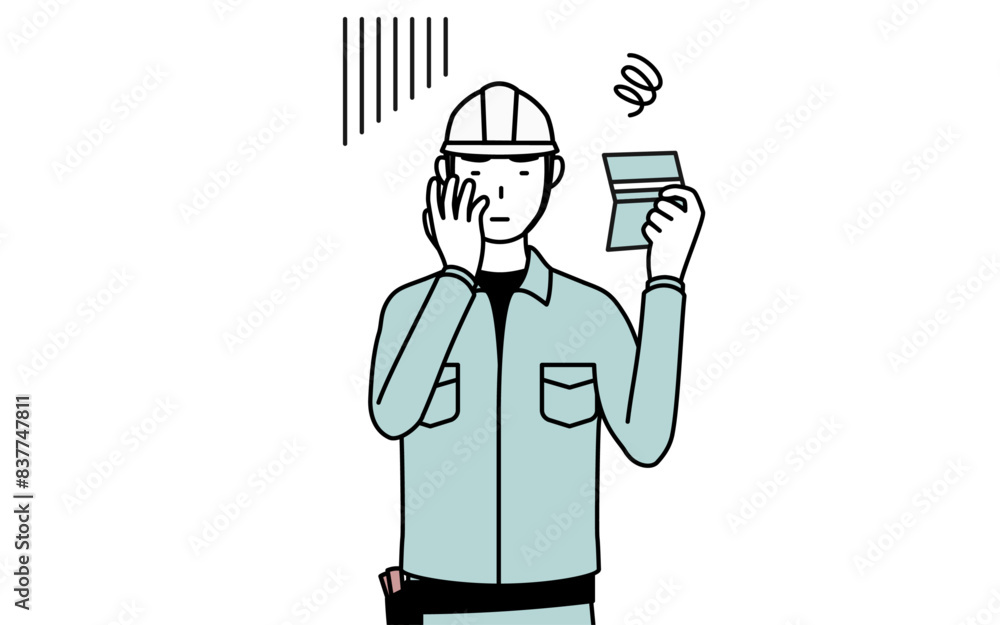 預金通帳を見て落ち込むヘルメットと作業着姿の男性