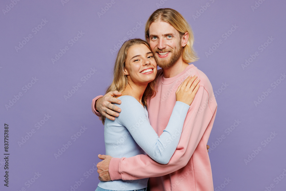 Side view young smiling fun couple two friends family man woman wear pink blue casual clothes together hug cuddle embrace look camera isolated on pastel plain light purple background studio portrait. Side view young smiling fun couple two friends family man woman wear pink blue casual clothes together hug cuddle embrace look camera isolated on pastel plain light purple background studio portrait.