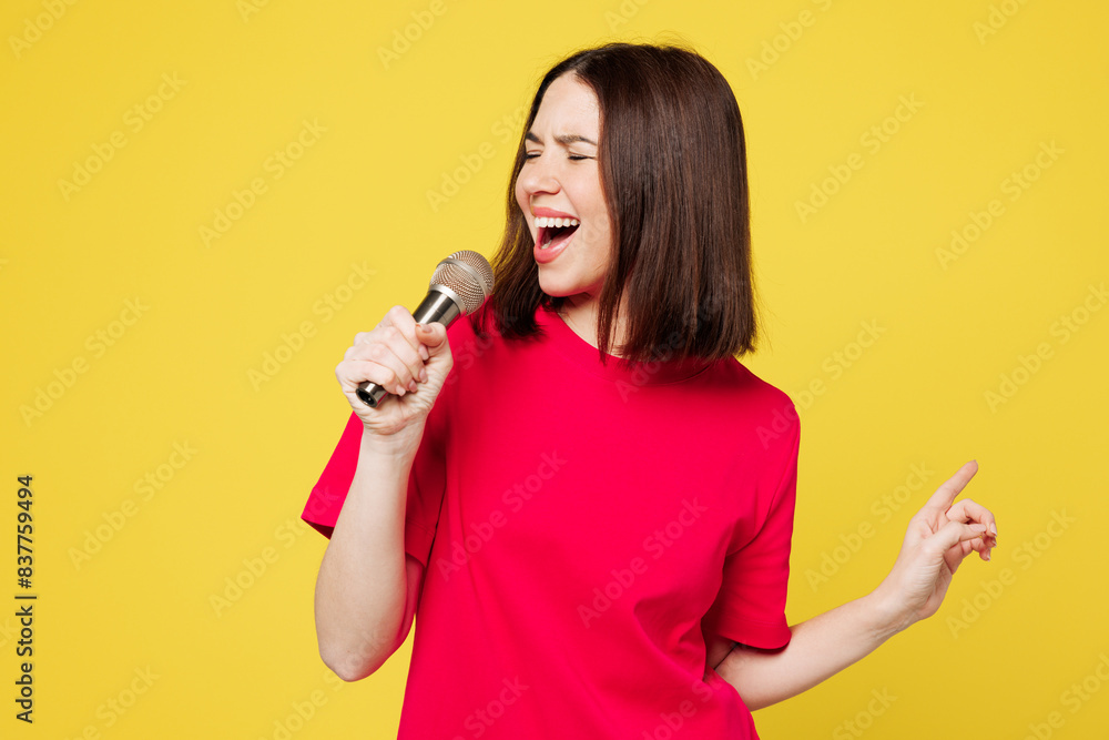 Young happy singer expressive Caucasian woman she wear pink t-shirt casual clothes sing song in microphone at karaoke club isolated on plain yellow orange background studio portrait Lifestyle concept Young happy singer expressive Caucasian woman she wear pink t-shirt casual clothes sing song in microphone at karaoke club isolated on plain yellow orange background studio portrait Lifestyle concept