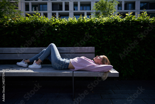 Woman lying down on bench at public park photo