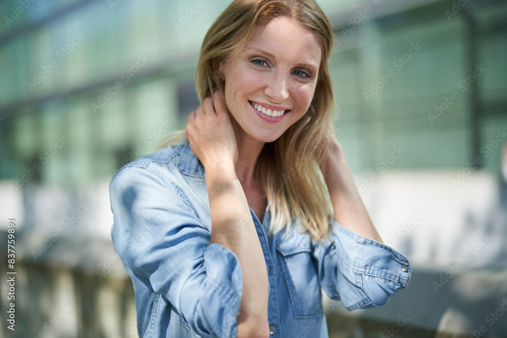 Smiling woman with hands in hair and wearing denim shirt Smiling woman with hands in hair and wearing denim shirt