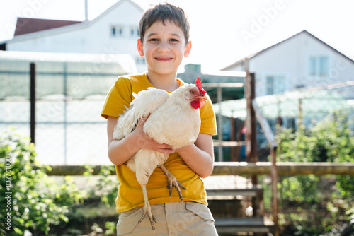Smiling boy with chicken in back yard photo